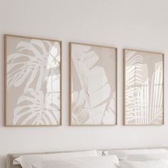 three paintings hang on the wall above a bed