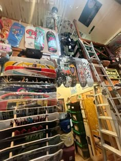 a room filled with lots of skateboards next to a metal ladder in front of a wall