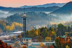 a city with mountains in the background and fog on the trees around it, as seen from an overlook point