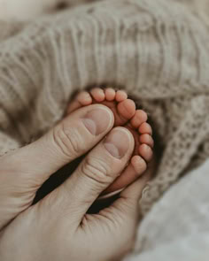 a person is holding their baby's foot in the middle of her hand, while laying down on a bed