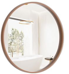 a white bath tub sitting next to a window under a round mirror on the wall