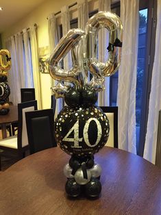 a table topped with balloons in the shape of an number 40 sitting on top of a wooden table