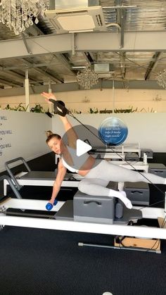 a woman is doing an exercise on a rowing machine in the middle of a room