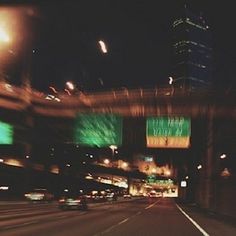 blurry photograph of city street at night with lights and billboards in the background