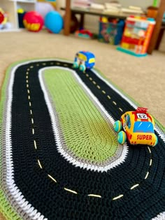 a crocheted rug with cars on the road and toys in the back ground