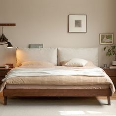 a bedroom with a bed, nightstands and pictures on the wall above it is shown