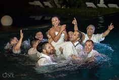 the bride and grooms are in the pool with their arms around each other as they laugh