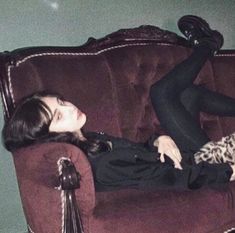 a woman laying on top of a brown couch