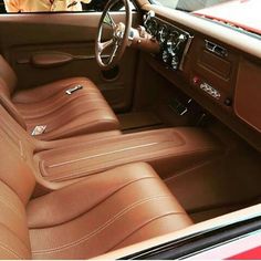 the interior of an old car with brown leather seats and steering wheel, in front of a man