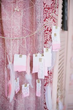 pink and white dream catchers hanging from a string with tags attached to the strings