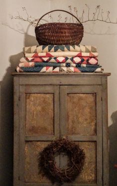 a basket sitting on top of a wooden cabinet next to a pile of blankets and pillows