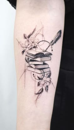 a black and white photo of a stack of books with flowers on the cover up