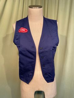 "This is a vintage, uniform vest from Acme Grocery store in the 60s or so.  It is deadstock in the original package. Made by Martin's Fashion Seal Uniform Group. Tagged a size small. The bust measures 16\" for a 32\" or so bust, see measurements below.  Made of a polyester and cotton blend in dark blue. It is a sleeveless vest with a V neck. It buttons up the front. On the right chest is an oval embroidered, red & white Acme patch. On the left chest is two reinforced holes where a name badge wou Vintage Workwear Vest Top, Vintage Cotton Vest With Button Closure, Vintage Vest Top For Work, Vintage Blue Sleeveless Vest, Retro Workwear Vest With Button Closure, Classic Blue Cotton Vest, Fitted Vintage Blue Vest, Blue Fitted Vintage Vest, Retro Sleeveless Vest For Work