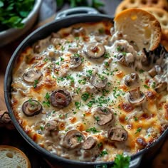 a casserole with mushrooms and cheese in a pan next to bread on the side