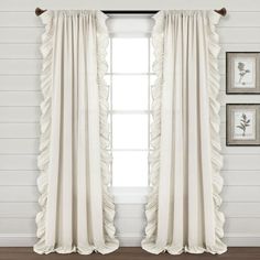 white curtains with ruffled edges hanging on the wall in front of two framed pictures