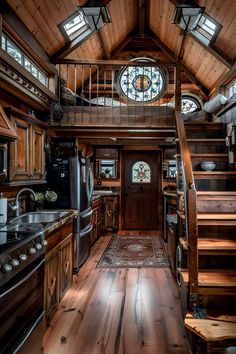 a kitchen with wooden floors and stairs leading up to the loft