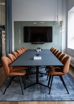 a large table with chairs and a television mounted on the wall in a conference room