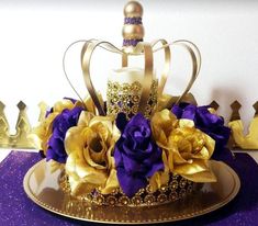 a crown with purple and gold flowers in it sitting on a plate next to other crowns