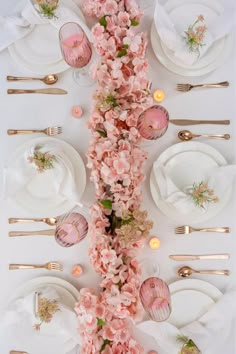 the table is set with pink flowers and gold place settings for an elegant dinner party