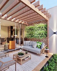 an outdoor living area with couches, tables and plants on the wall behind it