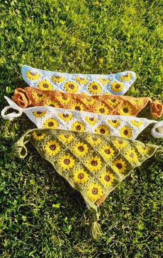 three crocheted sunflowers are laying on the grass