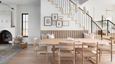 a dining room table with chairs and a bench in front of a staircase that leads up to the second floor