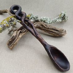 a wooden spoon sitting on top of a piece of driftwood next to some branches