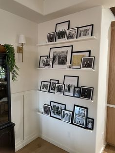 several black and white photos are arranged on the wall above a grandfather's clock