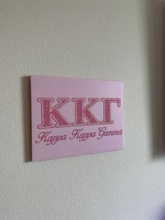 a pink sign hanging on the side of a white wall next to a blue vase