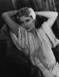 an old black and white photo of a woman laying on a couch with her hands behind her head