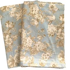 two pieces of blue and white floral fabric on top of each other, one is folded up