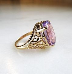 "This is a vintage 10K yellow gold filled filigree ladies ring. It is set with a large oval amethyst gemstone. The stone measures 11.9mm x 15.9mm. There is a natural inclusion in the amethyst that you will see throughout the pictures. The band is sized at a 7. Total weight of the ring is 5.3grams/3.4dwt. The band is stamped 10K inside. There is a hallmark that is an \"F\" inside a diamond shape. This is a vintage, previously owned ring. Therefore, light wear can be expected. There is no visible Amethyst Rings Vintage, Vintage Amethyst Ring With Intricate Design For Anniversary, Vintage Amethyst Ring With Intricate Design For Wedding, Gold Oval Amethyst Ring With Accent Stones, Heirloom Amethyst Filigree Ring For Anniversary, Gold Oval Amethyst Heirloom Ring, Gold Oval Heirloom Amethyst Ring, Classic Gold Amethyst Ring For Wedding, Heirloom Gold Oval Amethyst Ring