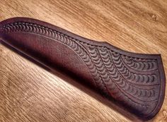 a close up of a wooden object on a table with wood grained surface and brown leather