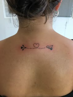 the back of a woman's shoulder with an arrow and heart tattoo