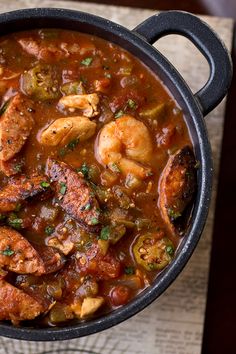 a pot filled with shrimp and sausage stew on top of a wooden table