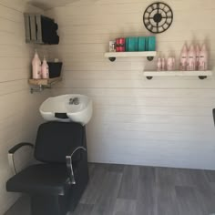 a chair and sink in a room with white walls, wood flooring and shelving