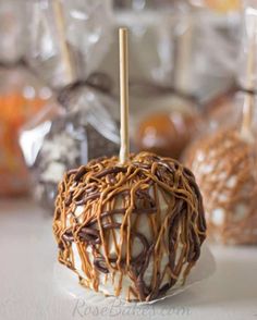 two caramel apples with chocolate drizzle and candy sticks on the top one