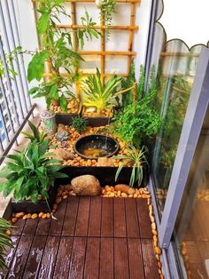 an indoor garden with plants and rocks on the floor next to a glass door that leads out onto a balcony