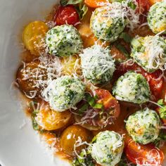 a white bowl filled with broccoli and tomatoes covered in parmesan cheese