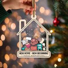 someone holding up a christmas ornament that says new home, new beginning with an image of a house