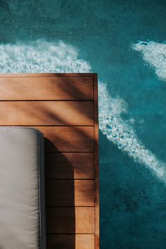 a chair sitting on top of a wooden floor next to a pool with blue water