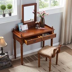 a wooden desk with a mirror, chair and flowers on it in front of a window