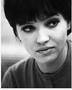 a black and white photo of a woman with short hair looking at the camera while wearing a sweater