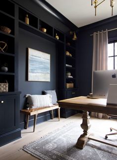 an office with black walls and white carpeted flooring, built in shelving units