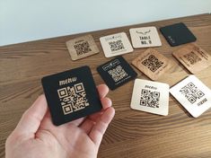 a hand holding a qr code next to some wooden coasters on a table