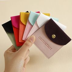 a hand holding a small wallet with five different colors