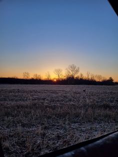 the sun is setting over an open field