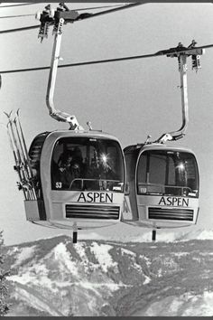 two ski lift cars with skiers on them going down the mountain side in black and white