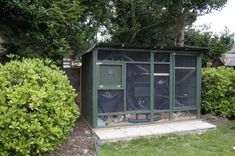 an outdoor toilet in the middle of some bushes and shrubbery, next to a fence