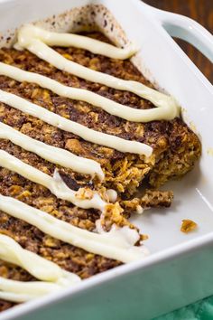 a white dish filled with carrot cake covered in icing